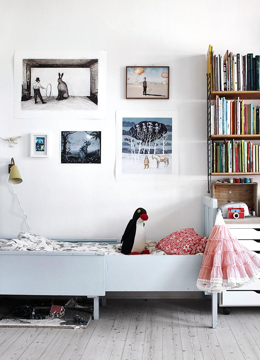 Børneværelse med enkel seng, bogreol, legetøj og billedvæg i lys skandinavisk indretning.