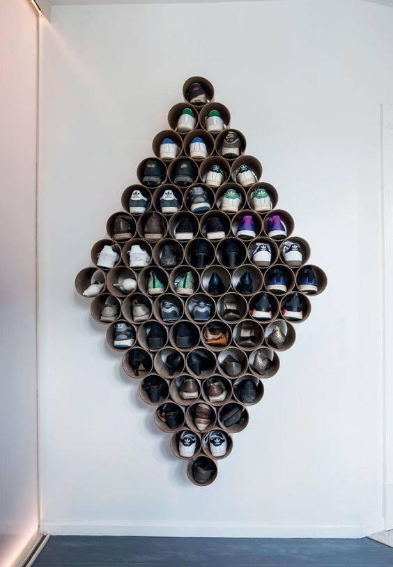 Vægmonteret skoopbevaring i rørformede rum arrangeret i diamantform på hvid væg.