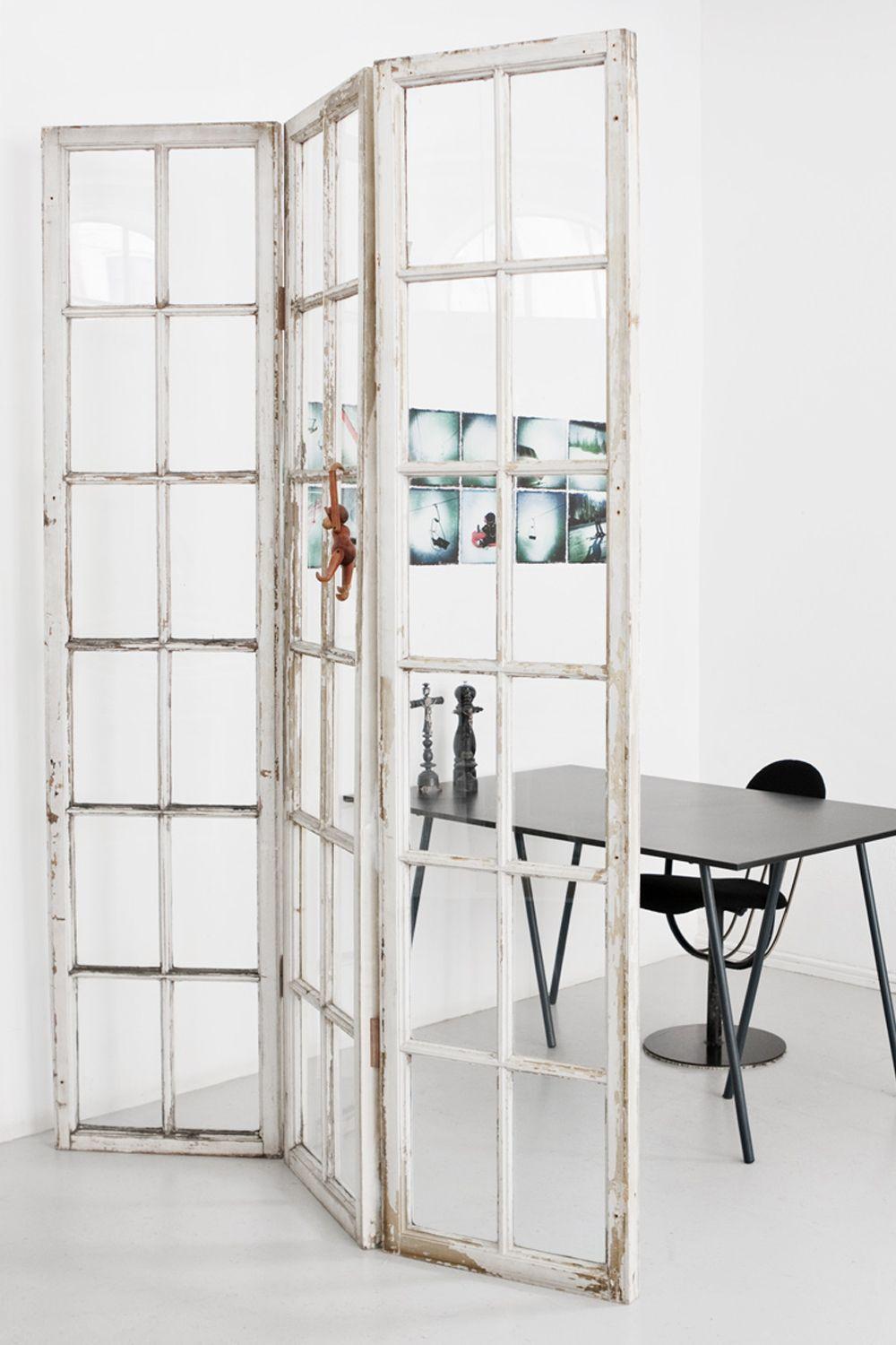 Fritstående rumdeler lavet af gamle hvidmalede glasdøre i rustik stil ved moderne bord og stol.